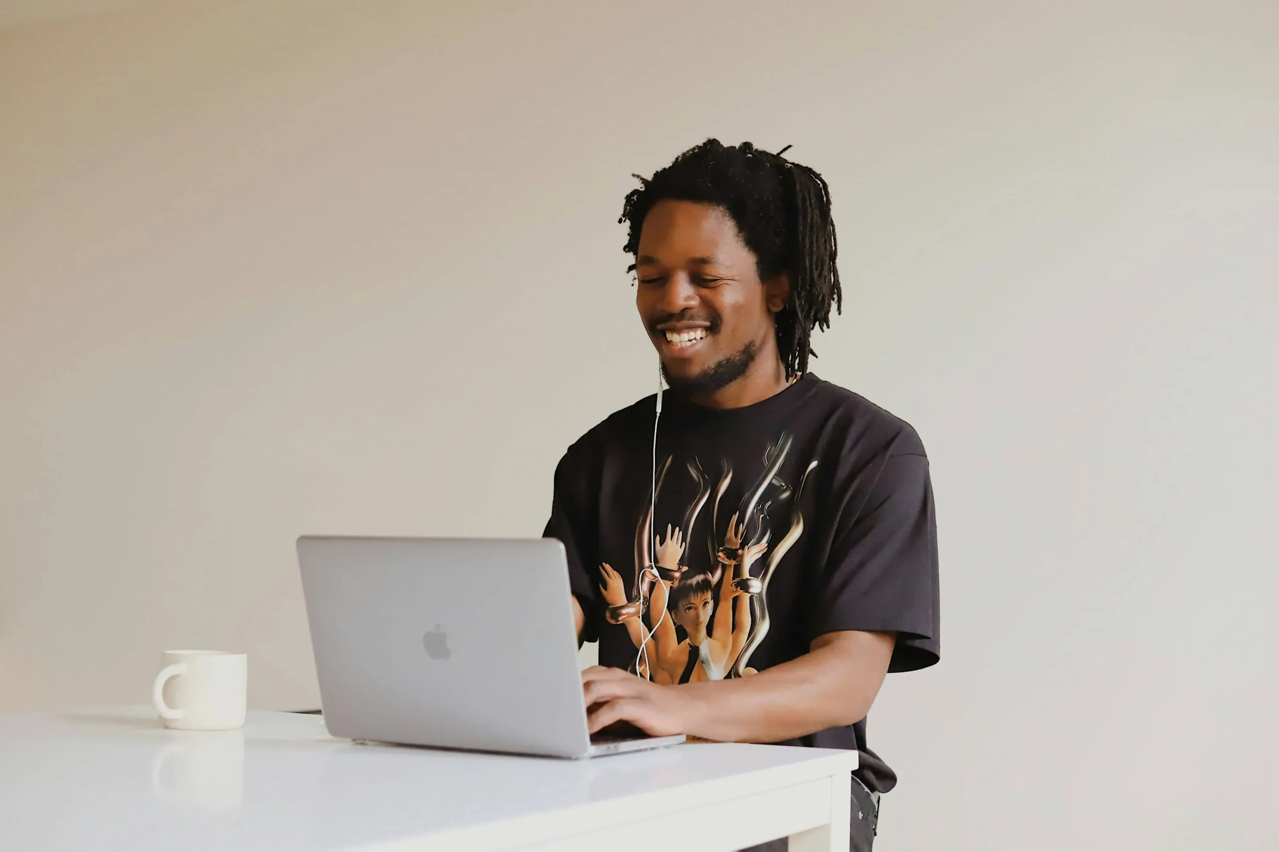 good-faces-DSj40n6beGk-unsplash_11zon rapaz negro sentado, mexendo no notebook com fones de ouvido.