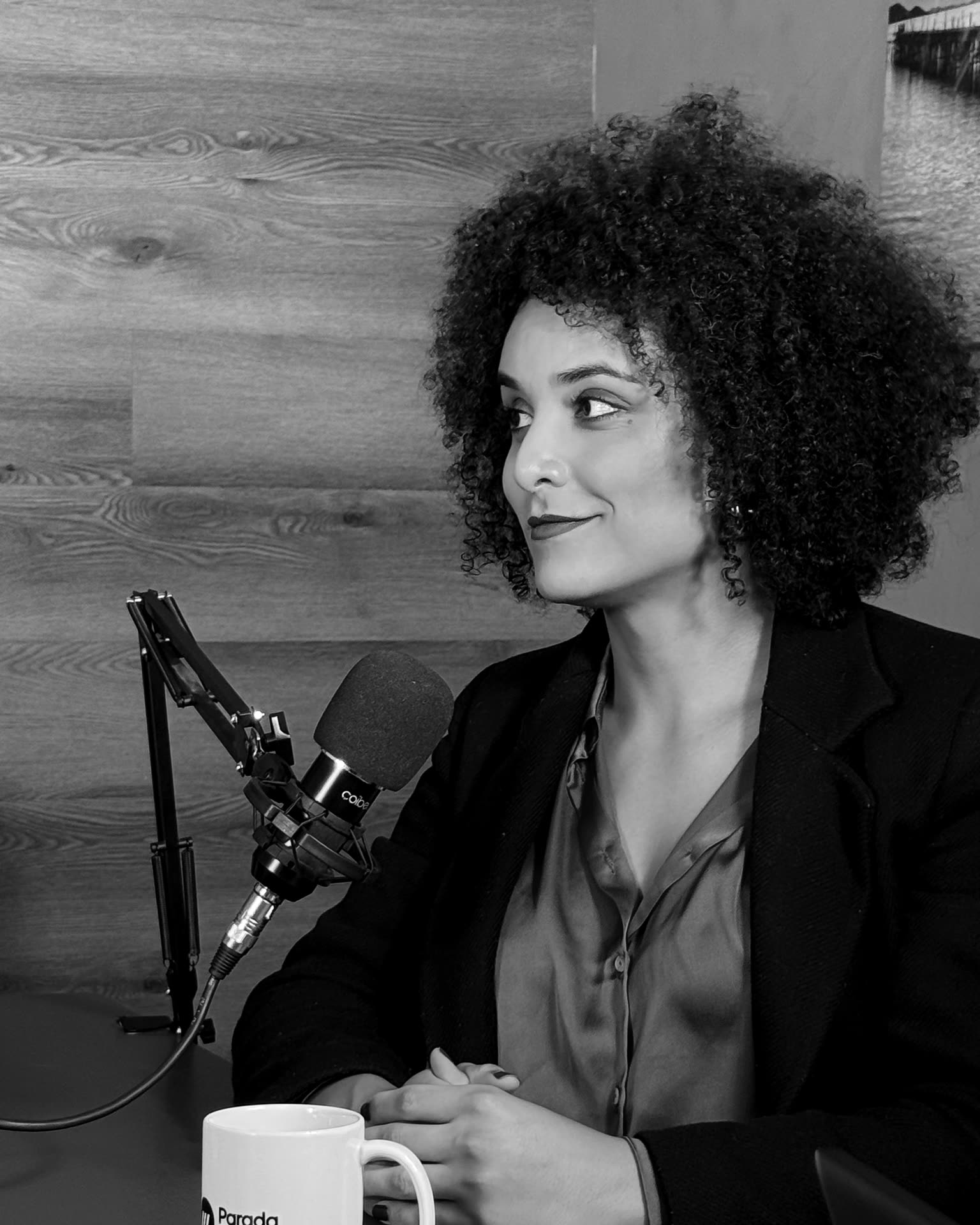 Retrato em preto e branco de Gabriela Augusto sentada em estúdio, ao microfone