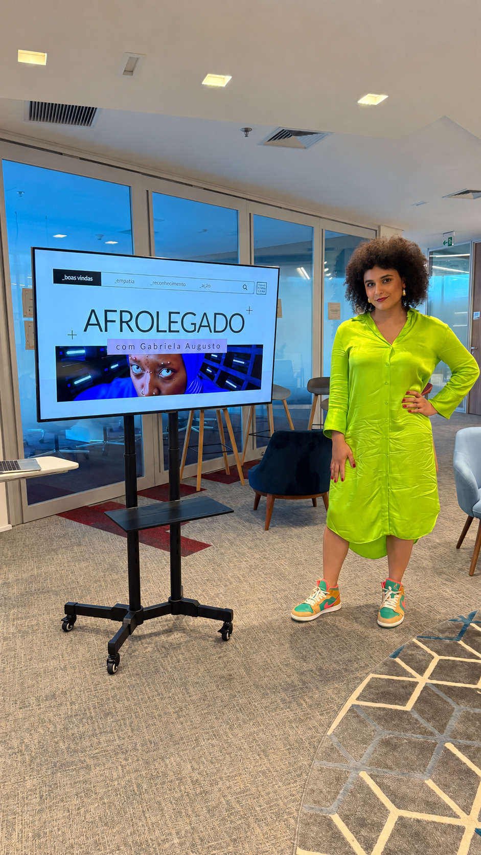 Gabriela Augusto de vestido verde ao lado de uma tela exibindo o painel do Afrolegado