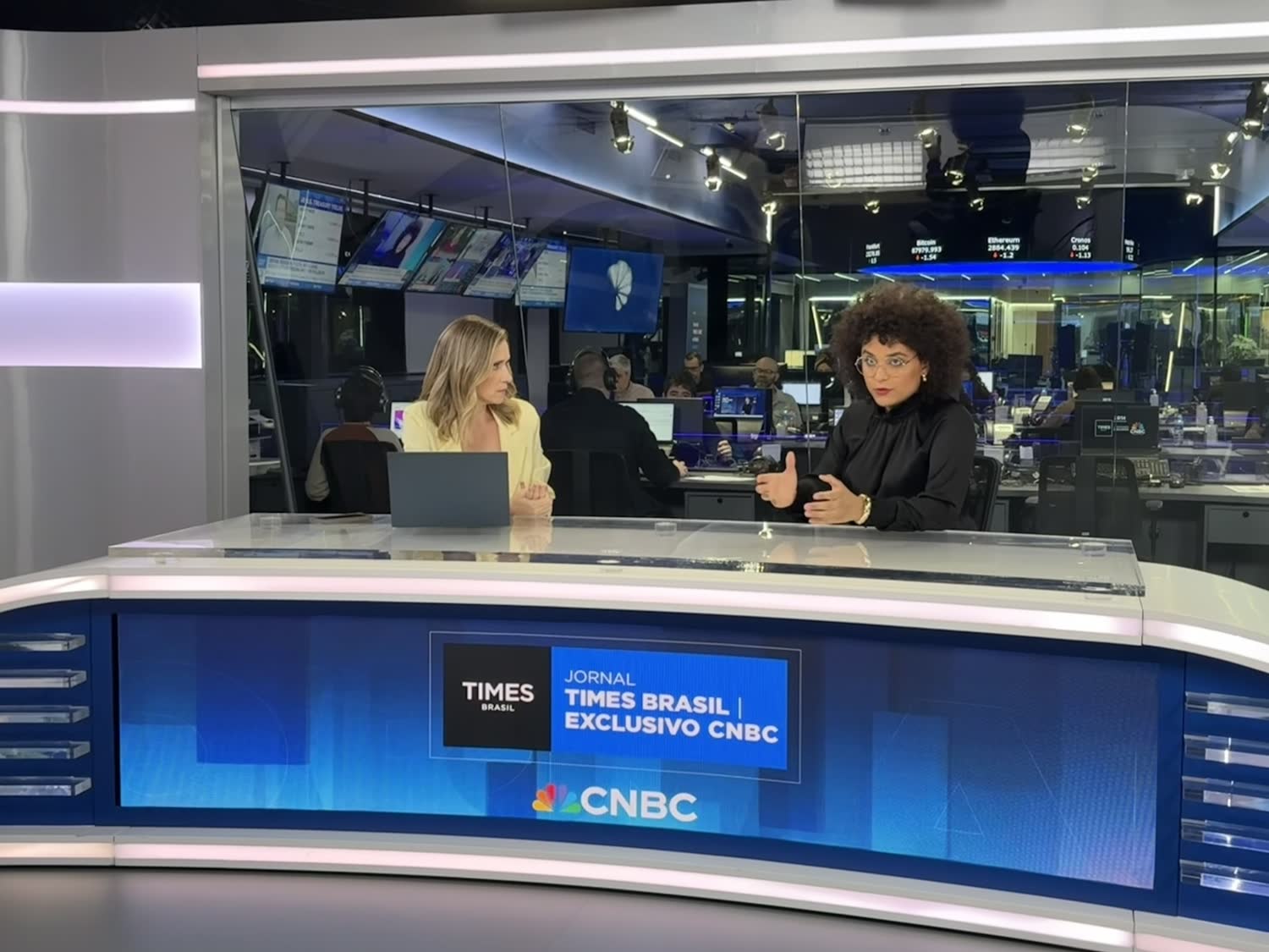 Gabriela Augusto em entrevista ao vivo no estúdio do Times Brasil, com bancada exibindo a logo da CNBC
