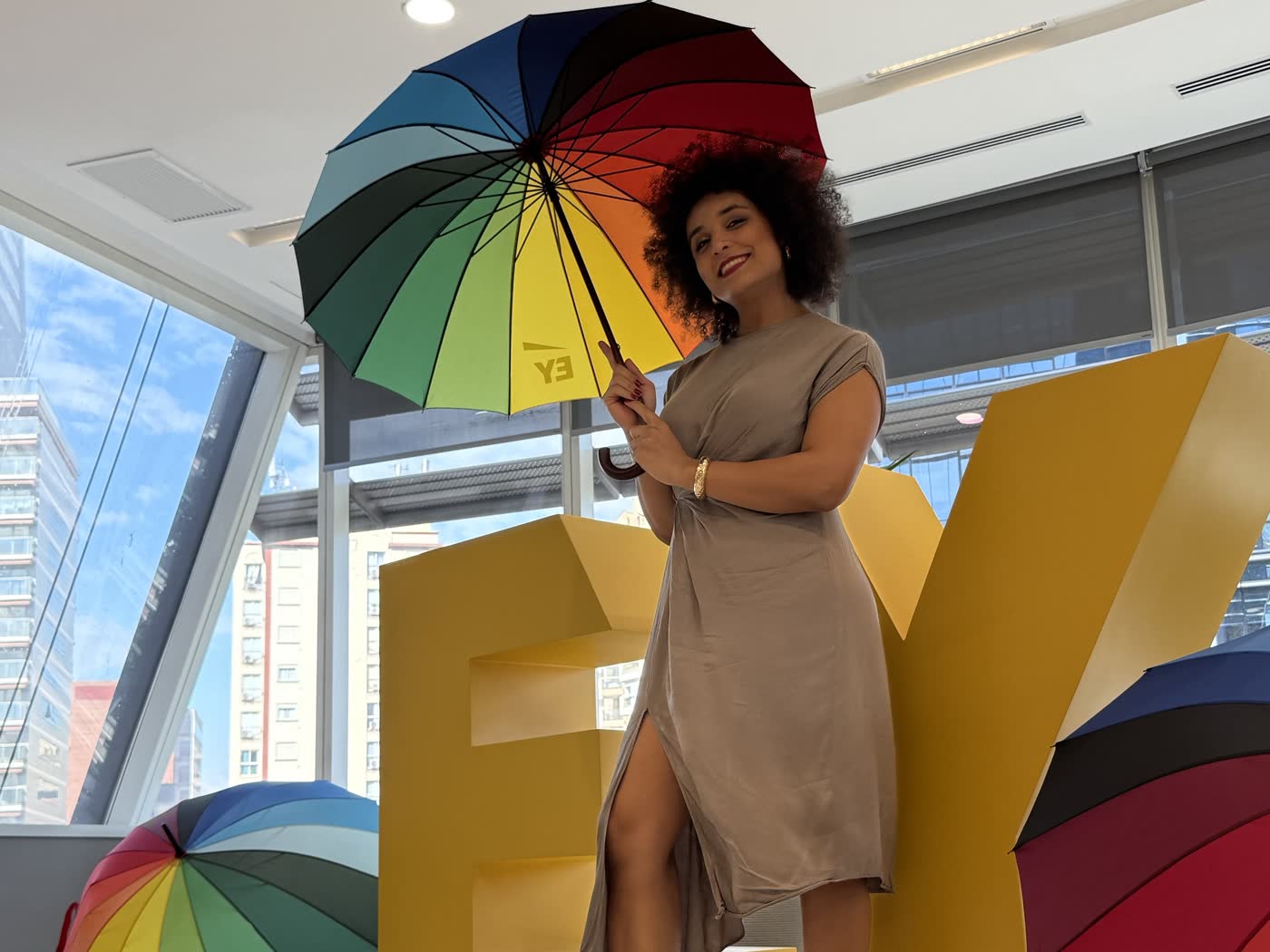 Gabriela Augusto em evento na sede da EY, ao lado de guarda-chuvas coloridos com a marca EY