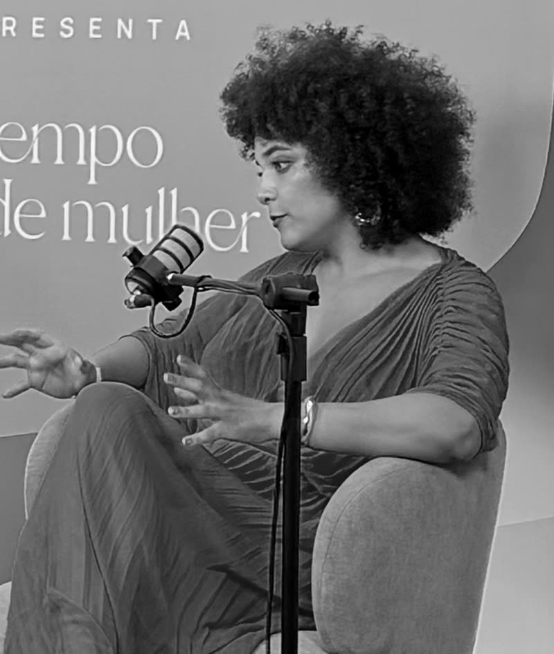 Retrato em preto e branco de Gabriela Augusto gesticulando ao microfone, de perfil